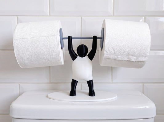 Front view of the Strongman toilet roll holder lifting two toilet rolls, standing on a white toilet cistern against metro tiles