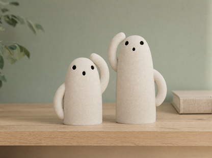 Pair of bone white ghost tea light holders on an oak shelf