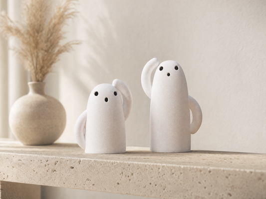 Pair of ivory white ghost tea light holders on a travertine shelf